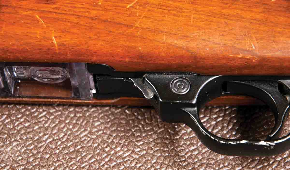 A steel thumb latch forward of the magazine release button locks the action open.